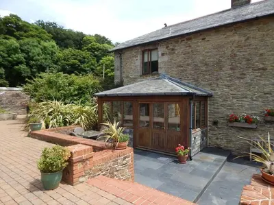 a greenhouse in front of a brick building with potted plants at Little Hendra at Hendra Barns in Newquay