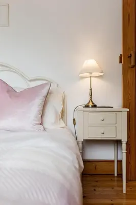 a white bed with a lamp on a night stand at Little Hendra at Hendra Barns in Newquay