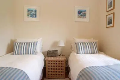 two twin beds in a bedroom with a night stand at Little Hendra at Hendra Barns in Newquay