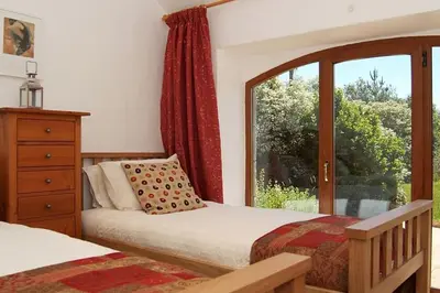 a bedroom with two beds and a window at The Old Coach House at Hendra Barns in Newquay