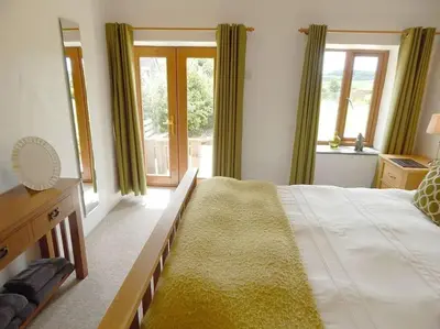 a large bedroom with a large bed and windows at The Old Coach House at Hendra Barns in Newquay