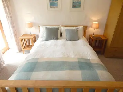 a bedroom with a large bed with two lamps at The Old Coach House at Hendra Barns in Newquay