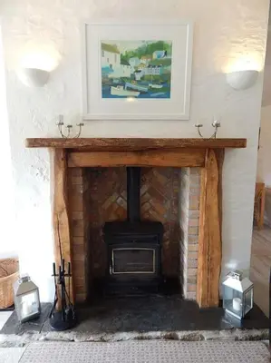 a fireplace in a living room with a picture above it at The Old Coach House at Hendra Barns in Newquay
