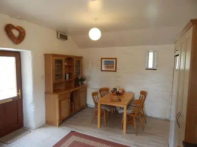 a dining room with a wooden table and chairs at The Old Coach House at Hendra Barns in Newquay
