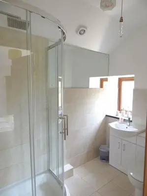a bathroom with a shower and a toilet and a sink at The Old Coach House at Hendra Barns in Newquay