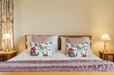 a bedroom with a bed with two pillows and two lamps at Hendra Barn at Hendra Barns in Newquay