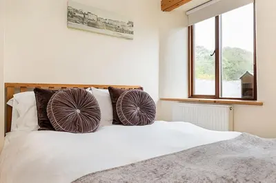 a bedroom with a bed with two pillows on it at Hendra Barn at Hendra Barns in Newquay