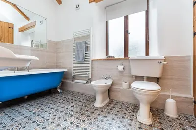 a bathroom with a tub and a toilet and a sink at Hendra Barn at Hendra Barns in Newquay