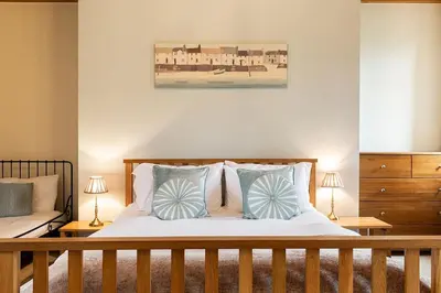 a bedroom with a bed with blue and white pillows at Hendra Barn at Hendra Barns in Newquay