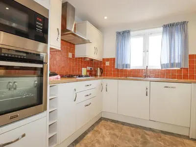 a kitchen with white cabinets and a microwave at Freefolk in Wadebridge