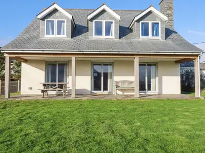a house with a bench on a lawn at Freefolk in Wadebridge
