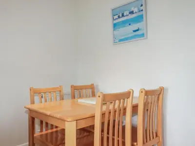 a wooden table with four chairs and a picture on the wall at Freefolk Cottage in Wadebridge
