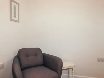 a chair in a room with a white wall at Freefolk Cottage in Wadebridge
