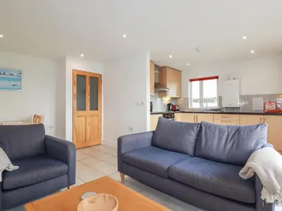 a living room with two blue couches and a kitchen at Freefolk Cottage in Wadebridge