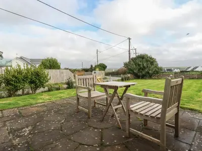 two benches and a table in a yard at Freefolk Cottage in Wadebridge