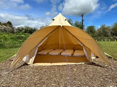 a tent with a bed in the middle of a field at Greenfinch Lakeside Bell Tent Basic with Airbeds Only in Saint Columb Major