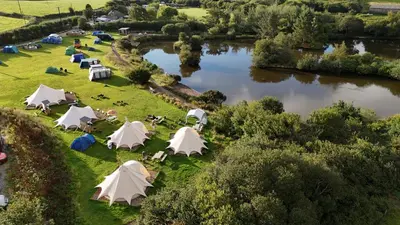 an aerial view of a group of tents next to a river at Greenfinch Lakeside Bell Tent Basic with Airbeds Only in Saint Columb Major