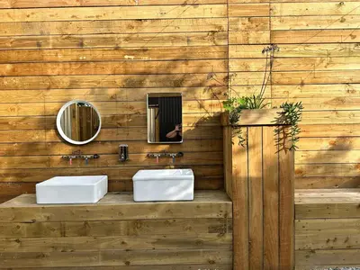a bathroom with two sinks on a wooden wall at Greenfinch Lakeside Bell Tent Basic with Airbeds Only in Saint Columb Major