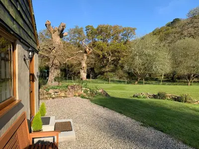 a house with a window and a grass field at Jasmine cottage in Liskeard