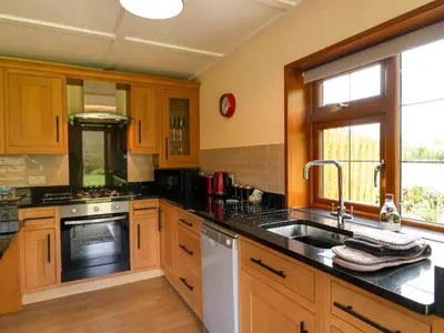 a kitchen with wooden cabinets and a sink at Jasmine cottage in Liskeard