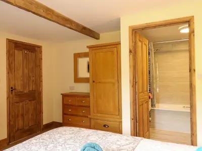 a bedroom with a bed and a dresser and a closet at Jasmine cottage in Liskeard