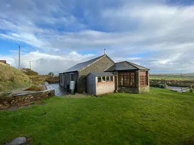 a small house in a field with a grass yard at Sundance Cottage Sleeps 4 in Camelford