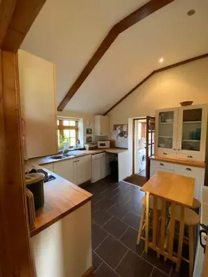 a kitchen with white cabinets and a table in it at Sundance Cottage Sleeps 4 in Camelford