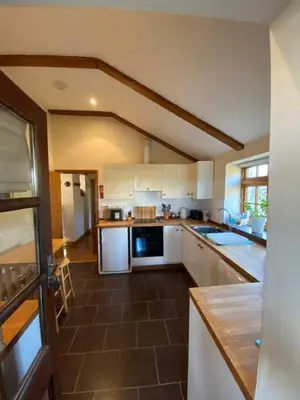 a kitchen with white cabinets and a brown tile floor at Sundance Cottage Sleeps 4 in Camelford