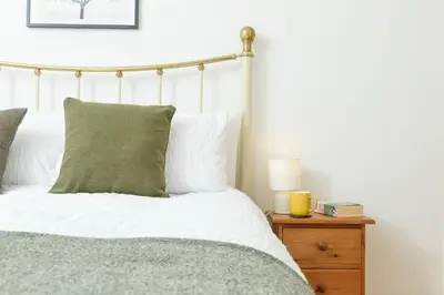 a bedroom with a bed with white sheets and a nightstand at Family Friendly Apartment above Praa Sands Beach in Praa Sands