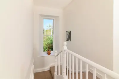a white staircase in a home with a window at Family Friendly Apartment above Praa Sands Beach in Praa Sands