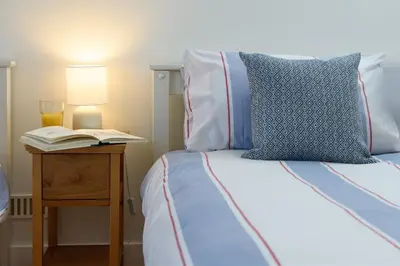 a bed with a book and a lamp on a night stand at Family Friendly Apartment above Praa Sands Beach in Praa Sands