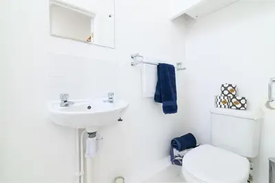 a white bathroom with a toilet and a sink at Family Friendly Apartment above Praa Sands Beach in Praa Sands