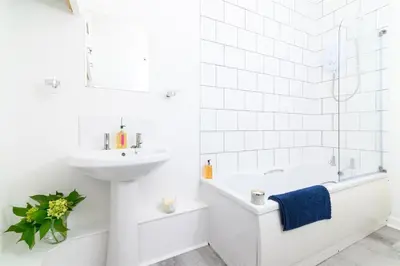 a white bathroom with a sink and a tub and a toilet at Family Friendly Apartment above Praa Sands Beach in Praa Sands