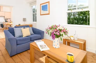 a living room with a blue couch and a table at Family Friendly Apartment above Praa Sands Beach in Praa Sands