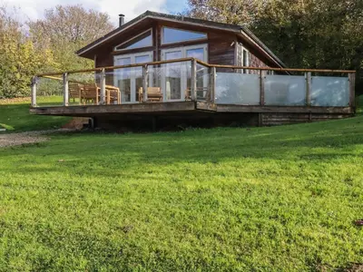 a house with a large deck on a grass field at 3 Hedgerows in Looe