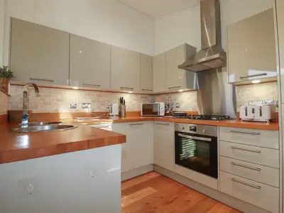 a kitchen with white cabinets and a stove top oven at 3 Hedgerows in Looe