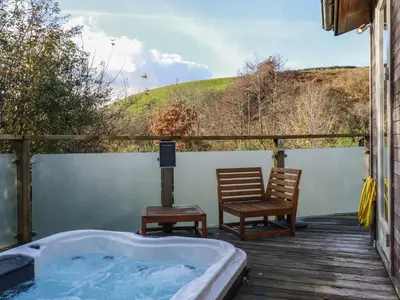 a hot tub and two chairs on a deck at 3 Hedgerows in Looe