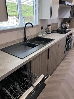 a kitchen with a sink and an open dishwasher at Valley View - Newquay Bay Resort near Porth Beach in Newquay