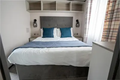a bedroom with a large bed with blue pillows at Valley View - Newquay Bay Resort near Porth Beach in Newquay