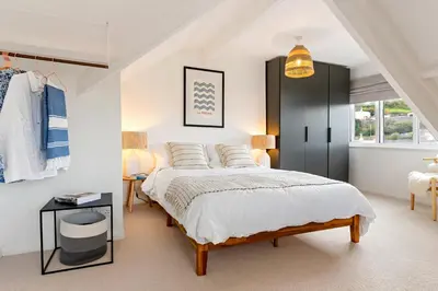 a bedroom with a large bed and a black cabinet at Waterside cottage - log burner - 10 mins to Falmouth in Flushing