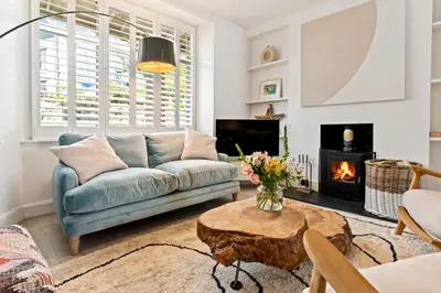 a living room with a blue couch and a fireplace at Waterside cottage - log burner - 10 mins to Falmouth in Flushing