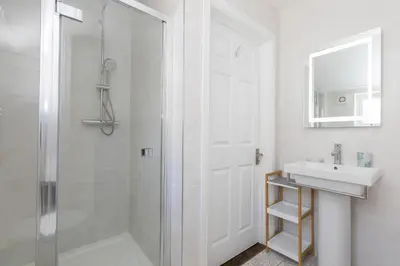 a white bathroom with a shower and a sink at Captain's Rest in St Ives