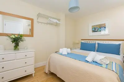 a bedroom with a bed and a dresser and a mirror at Captain's Rest in St Ives
