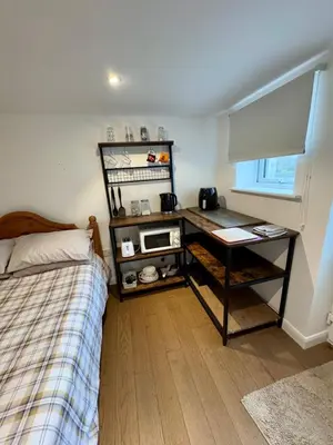 a bedroom with a bed and a desk with a microwave at The Shack 1 bedroom apartment in Newquay