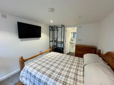 a bedroom with a bed and a tv on the wall at The Shack 1 bedroom apartment in Newquay