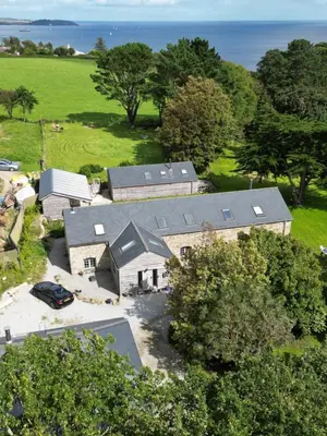 an aerial view of a house with trees and the ocean at Bream Barn - sea view, woodburner, easy walk to the beach, parking, full kitchen in Falmouth