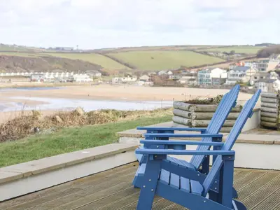 a blue rocking chair sitting on a porch overlooking a beach at Catch the Wave in Newquay