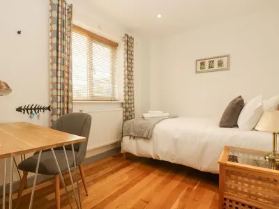 a bedroom with a bed and a table and a desk at Catch the Wave in Newquay