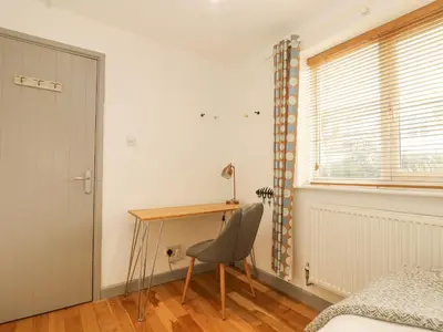 a bedroom with a desk and a chair next to a window at Catch the Wave in Newquay