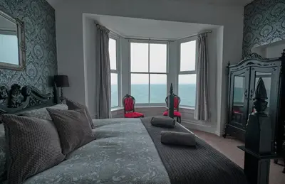a bedroom with a bed with a view of the ocean at Beacon Crag in Porthleven